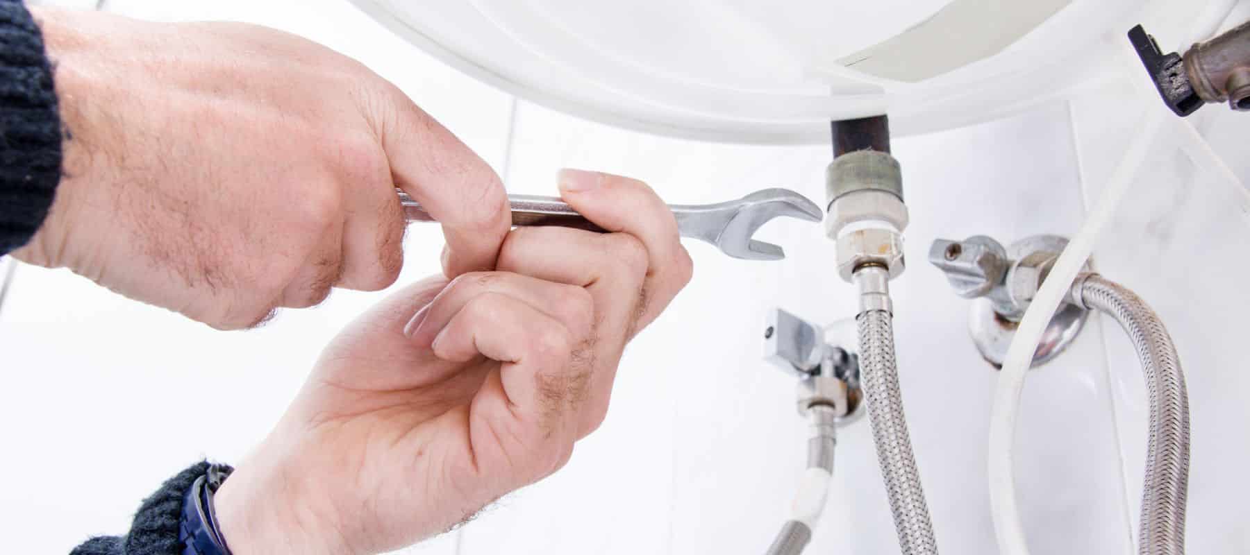 plumber using a handheld wrench to tighten a small fitting
