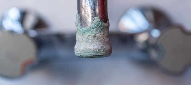 closeup of a faucet with a large amount of mineral deposit
