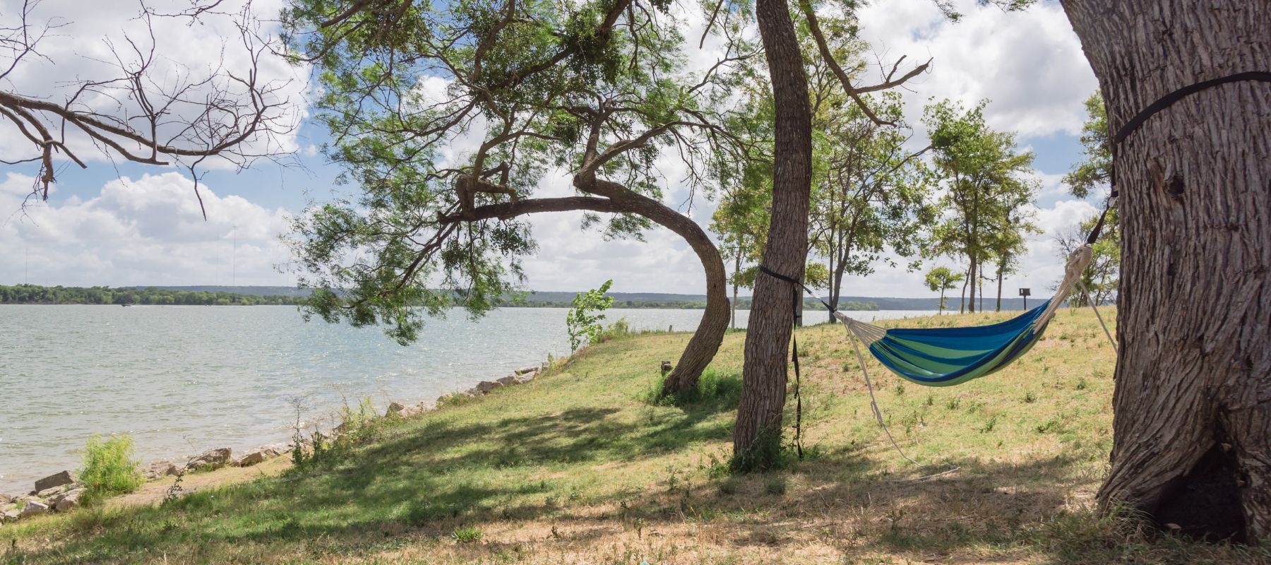 hammock hanging between trees by a lakeside