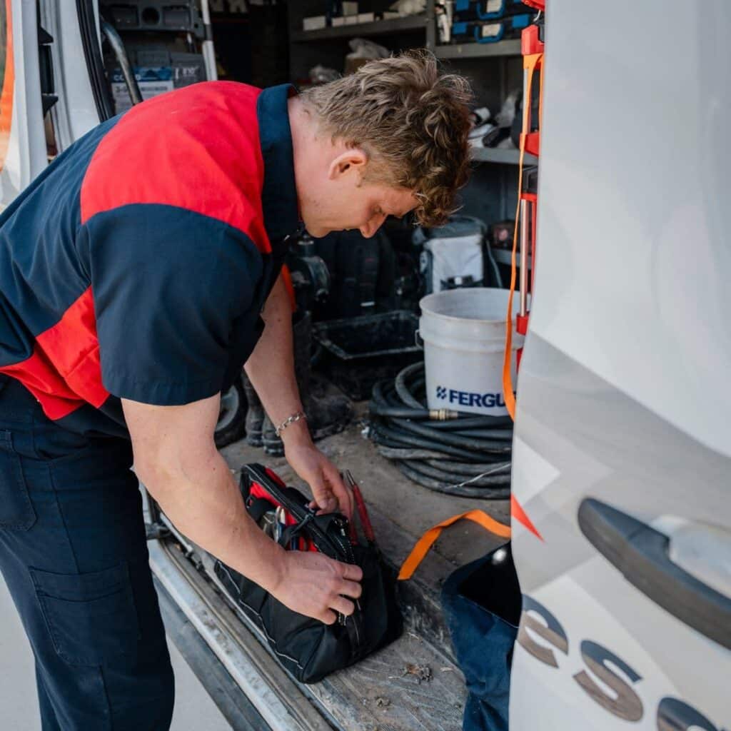 Plumber retrieving tools from the back of a service van