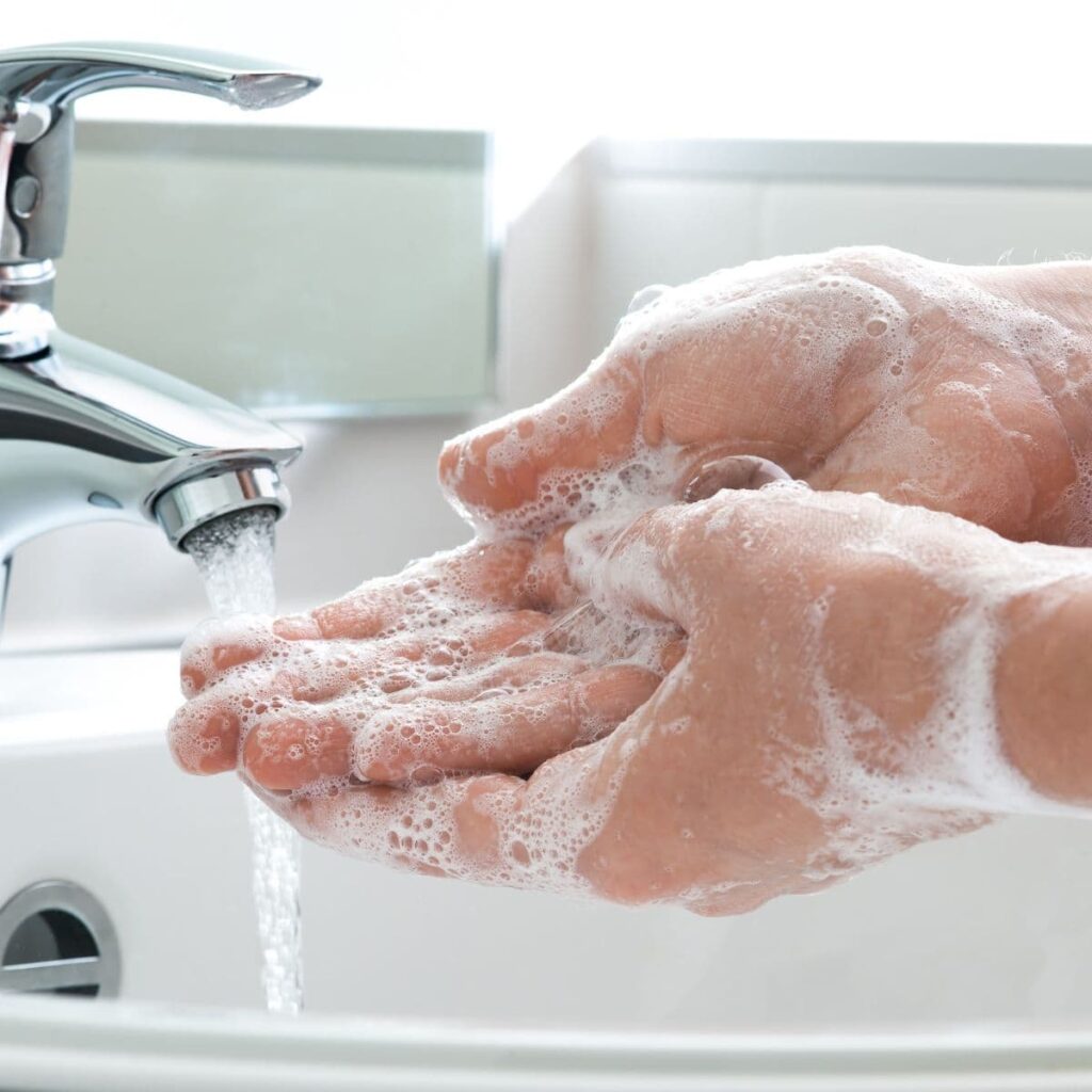 close-up of hands being washed with soap under running water