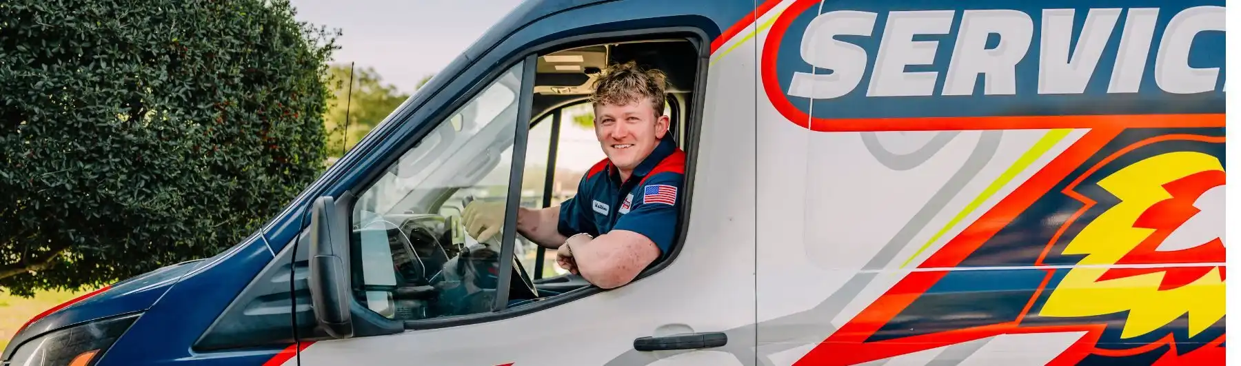 tech leaning out of the truck smiling