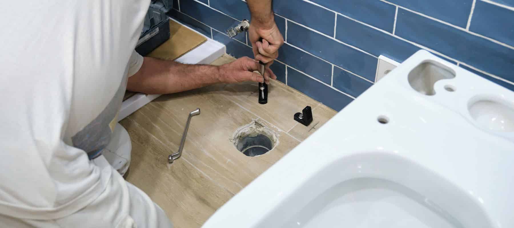 Worker installing or replacing a toilet base in a bathroom