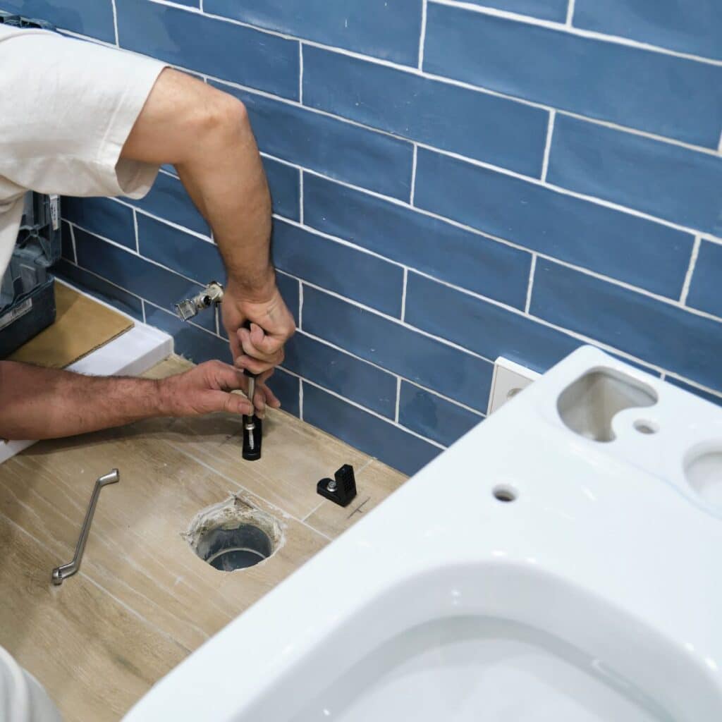 Worker installing or replacing a toilet base in a bathroom