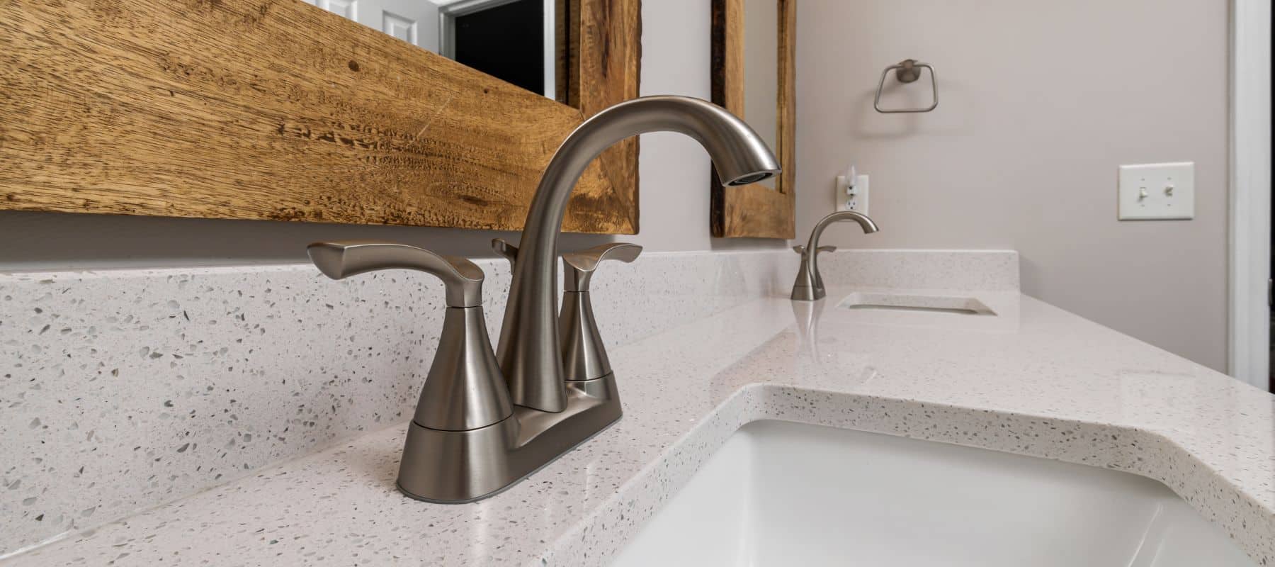 Modern bathroom sink with brushed nickel faucet and wooden framed mirror