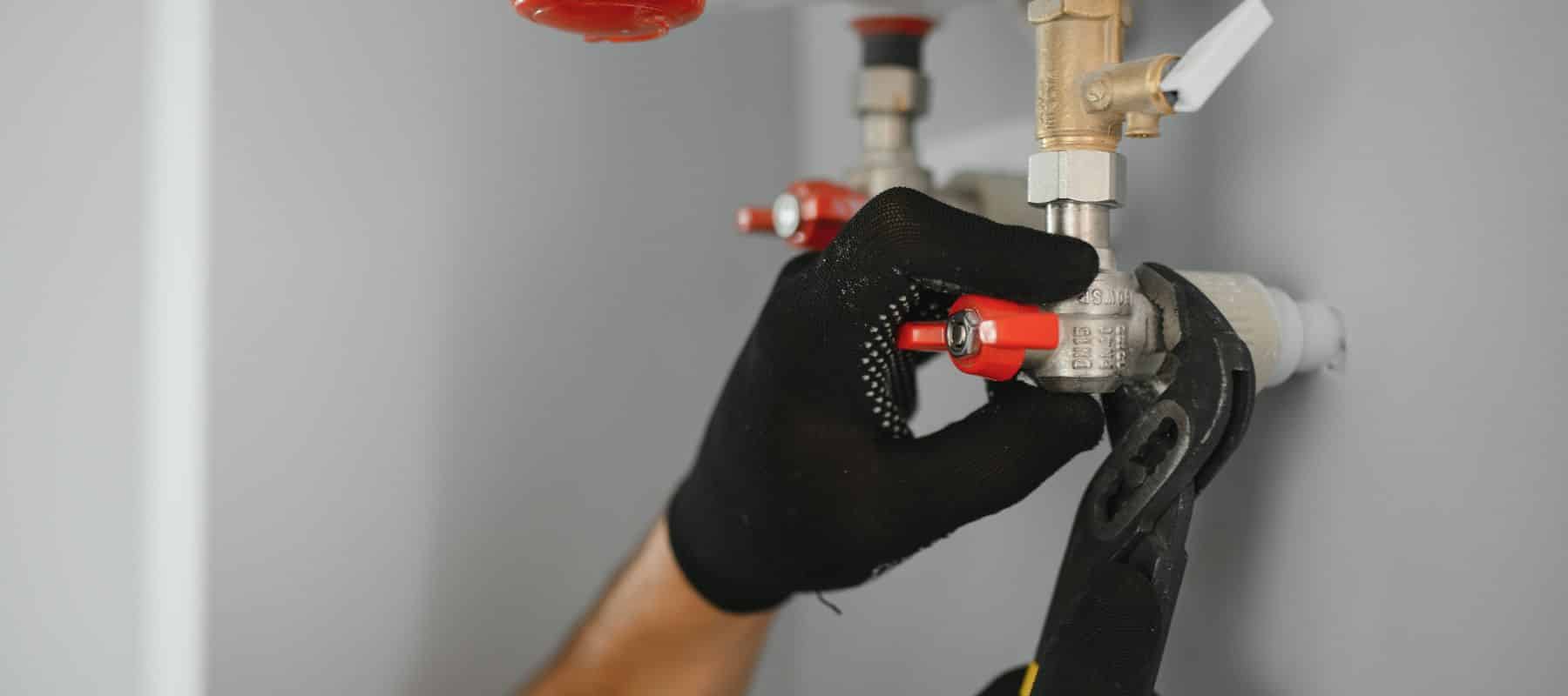 Technician adjusting a red-handled gas valve with a wrench