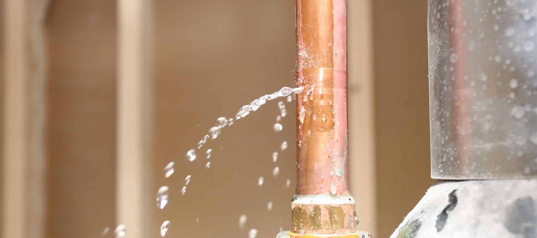 Water spraying from a small leak in a copper pipe