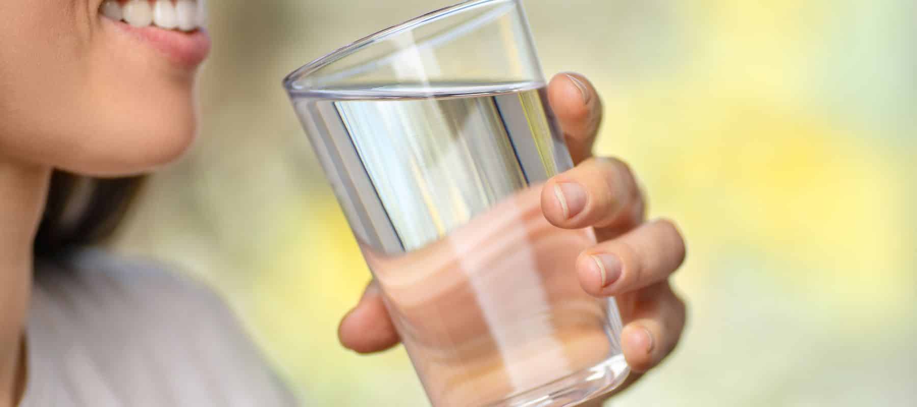 Person holding a clear glass of clean drinking water