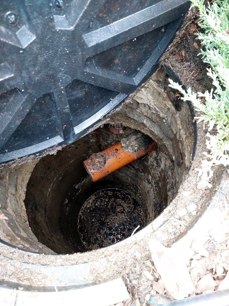 Small access point opened into a sewer cleanout, used for trenchless pipe repair without full excavation