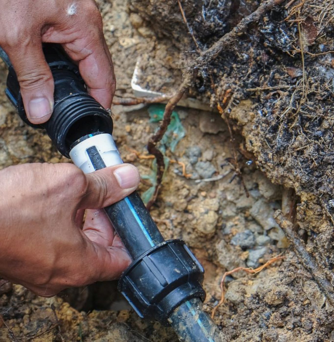 Close-up of hands repairing a water line outdoors in University Park, Texas